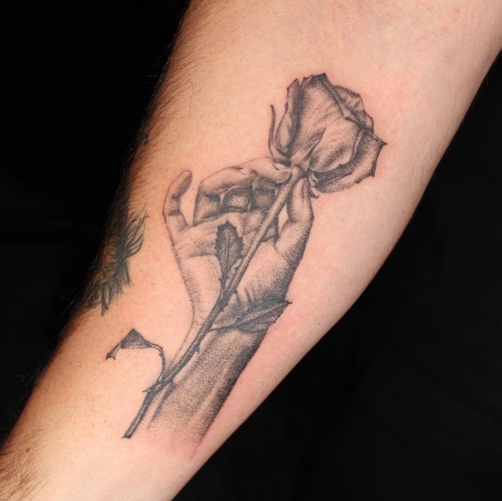 Fineline tattoo of a hand holding a rose