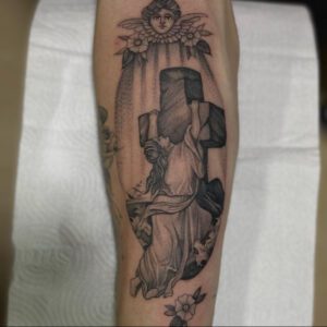 Tattooed depiction of Mary hanging onto a large stone cross