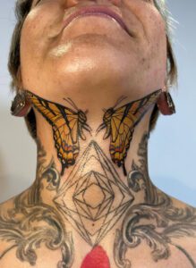 Pair of swallowtails tattooed on the throat and jaw made by Connor Muhs