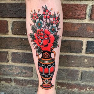 An American Traditional styled tattoo of a vase filled with a rose and pinwheel flowers