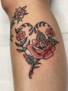 American Traditrional styled tattoo of a rose with vines that make a heart shape