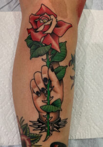 A tattoo of a punk hand holding a rose