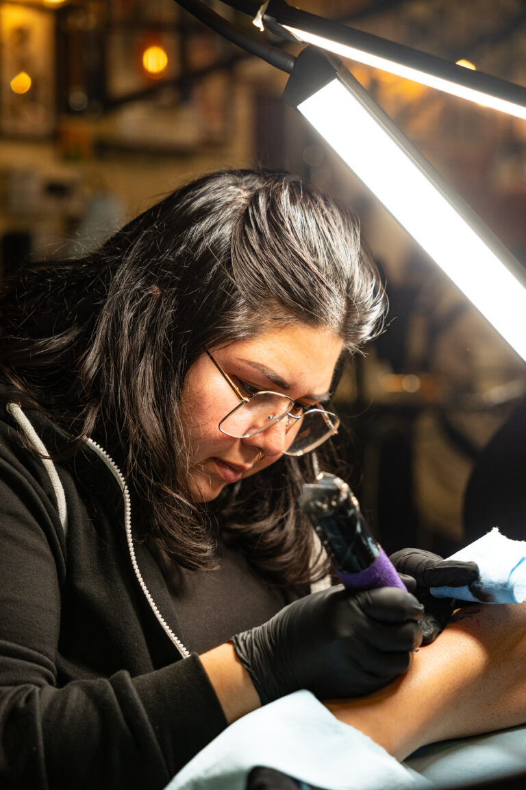 Action portrait of Lili Ann tattooing.